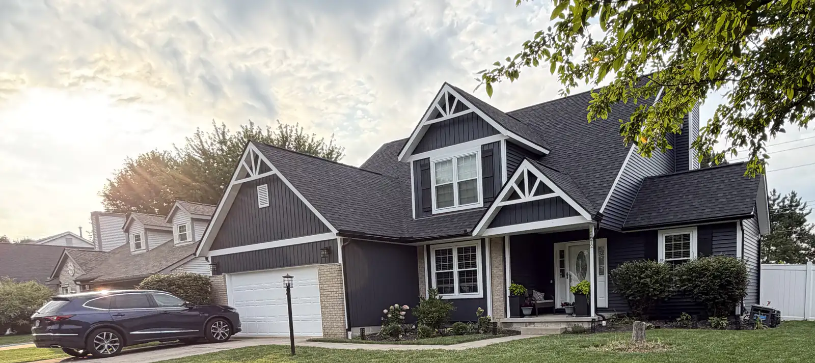 Two-story Central Ohio home with new navy siding, white trim and white gable accents installed by Lifetime Roofing Company