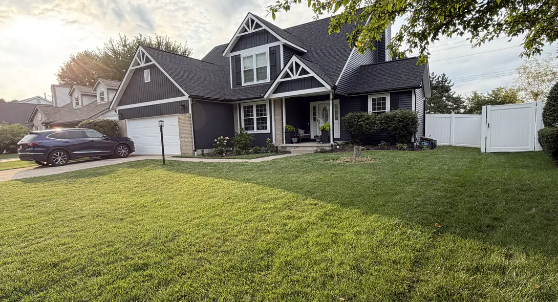 After: two-story home with new dark navy siding, white trim and white board-and-batten gable accents